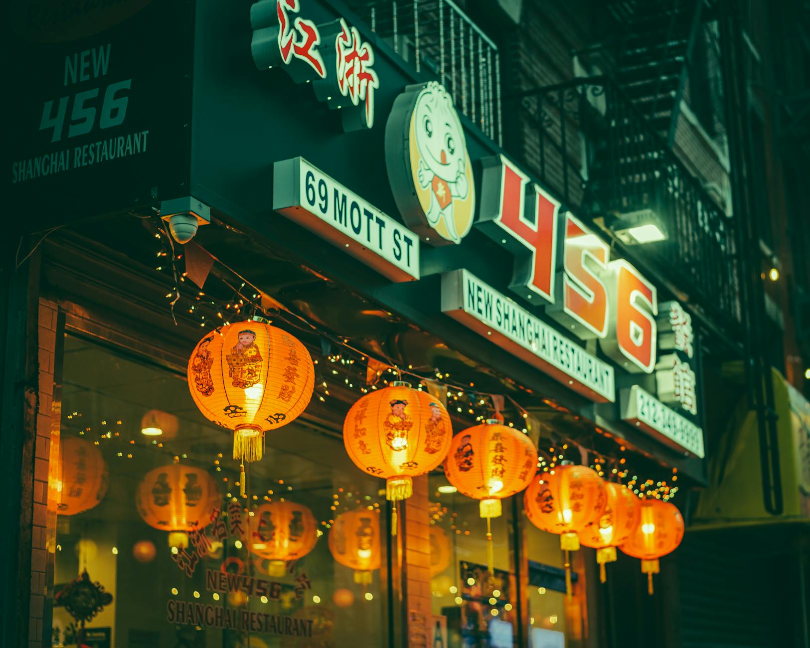 Vibrant exterior of New Shanghai Restaurant on Mott Street, NYC, adorned with lanterns at night.