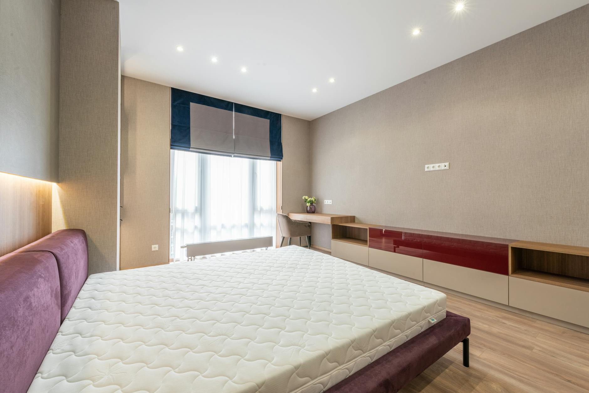 Spacious modern bedroom with a large window and minimalist decor, emphasizing natural light.