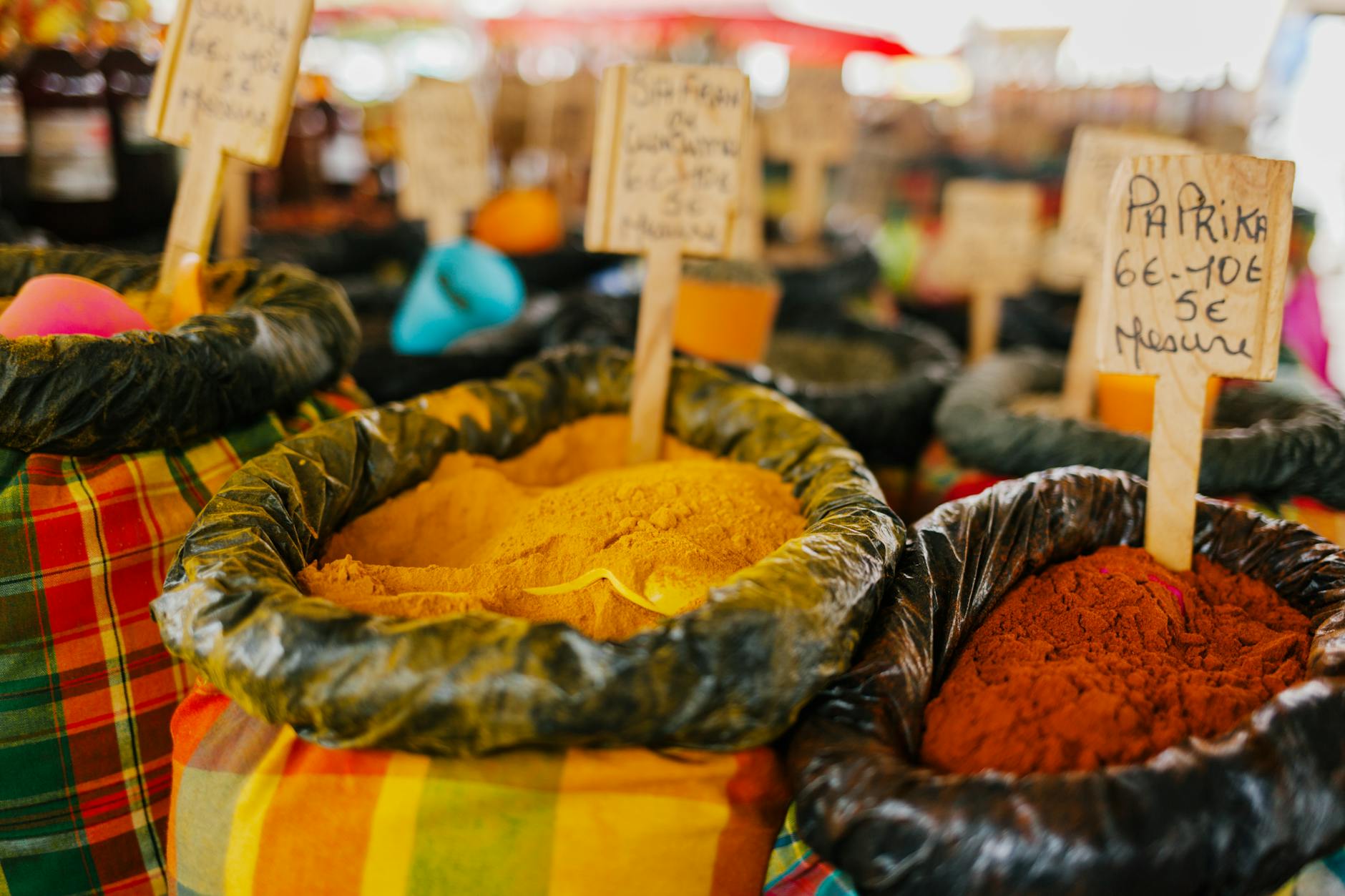Colorful spices and seasonings on display at a vibrant outdoor market, featuring paprika and other assorted flavors.